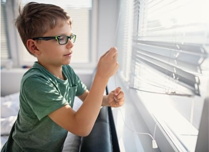 child opening window blinds